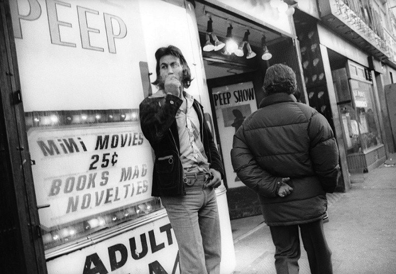 Man smoking outside adult theater, 1970s