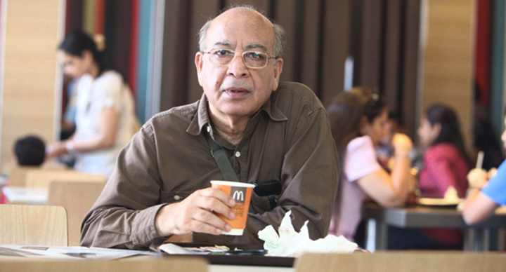 Older man sitting alone at McDonald's drinking coffee