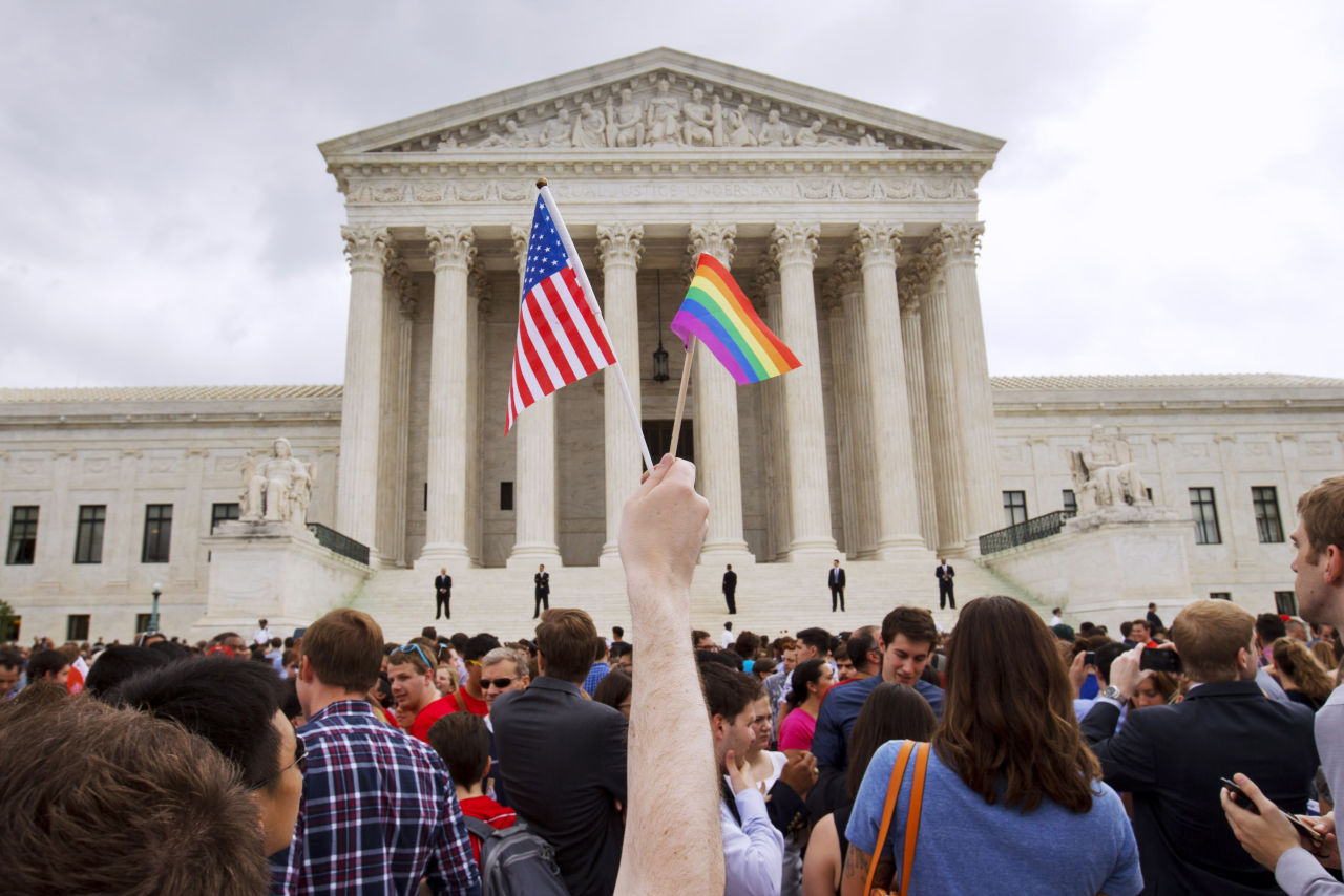 Person holding gay pride flag at protest in D.C.