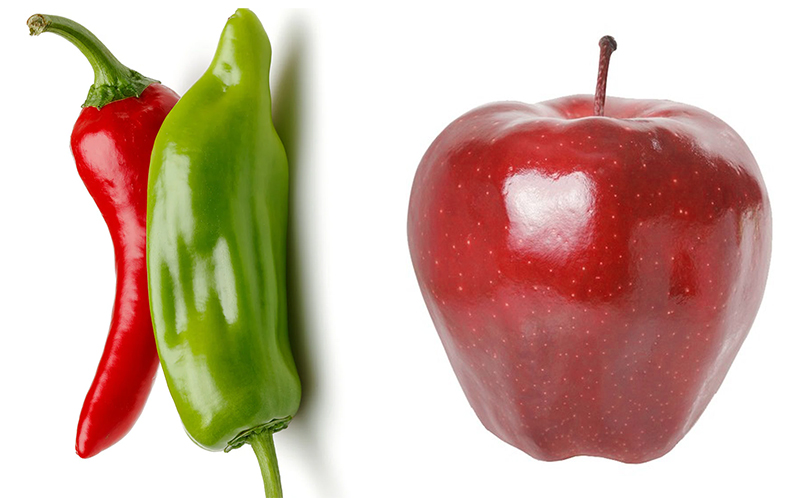 Red and green chili peppers beside a red apple