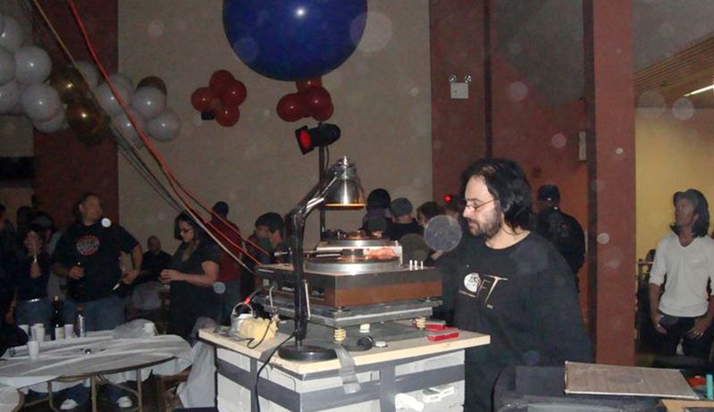 David Mancuso DJing on an elevated turntable in a room full of people and decorated with balloons