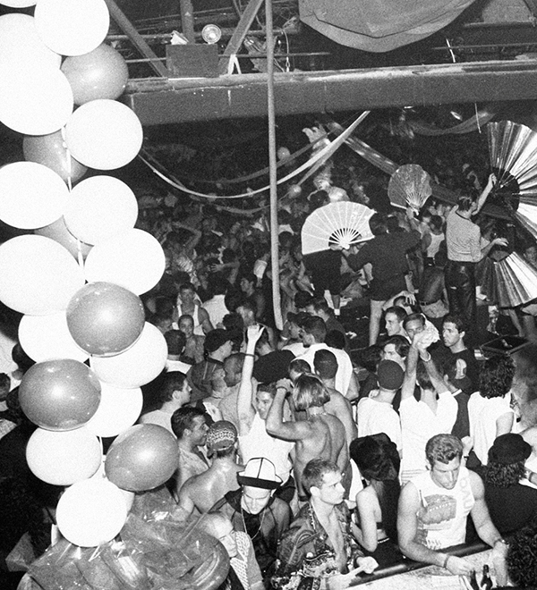 Crowd at The Roxy with clubgoers holding large fans on platforms with balloons in foreground
