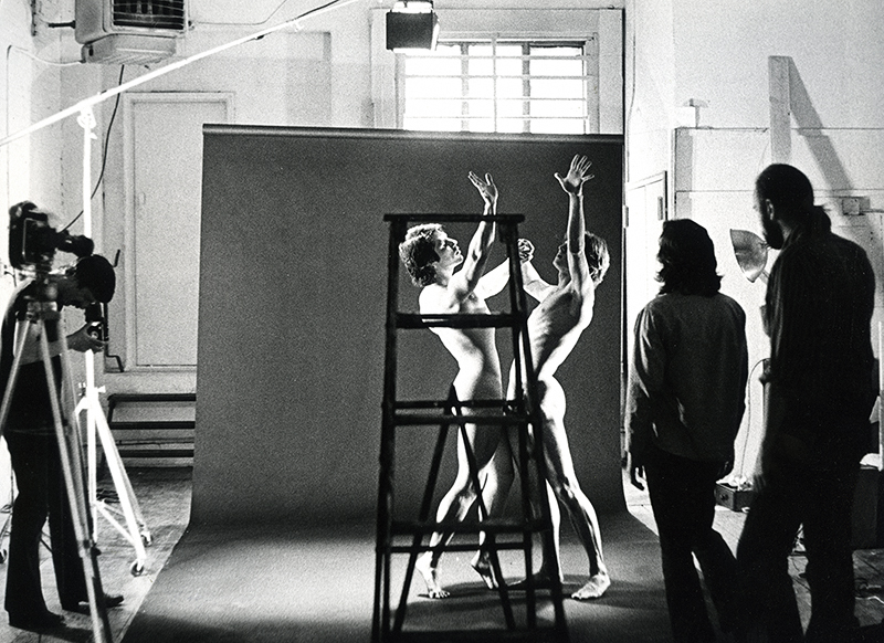 Frank Ross taking a photo and Chirstopher Rage and Arch Brown, from behind, watching dancers perform on the set of The Night Before