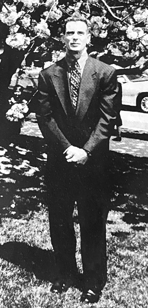 Black-and-white photo of Will standing outdoors wearing a suit